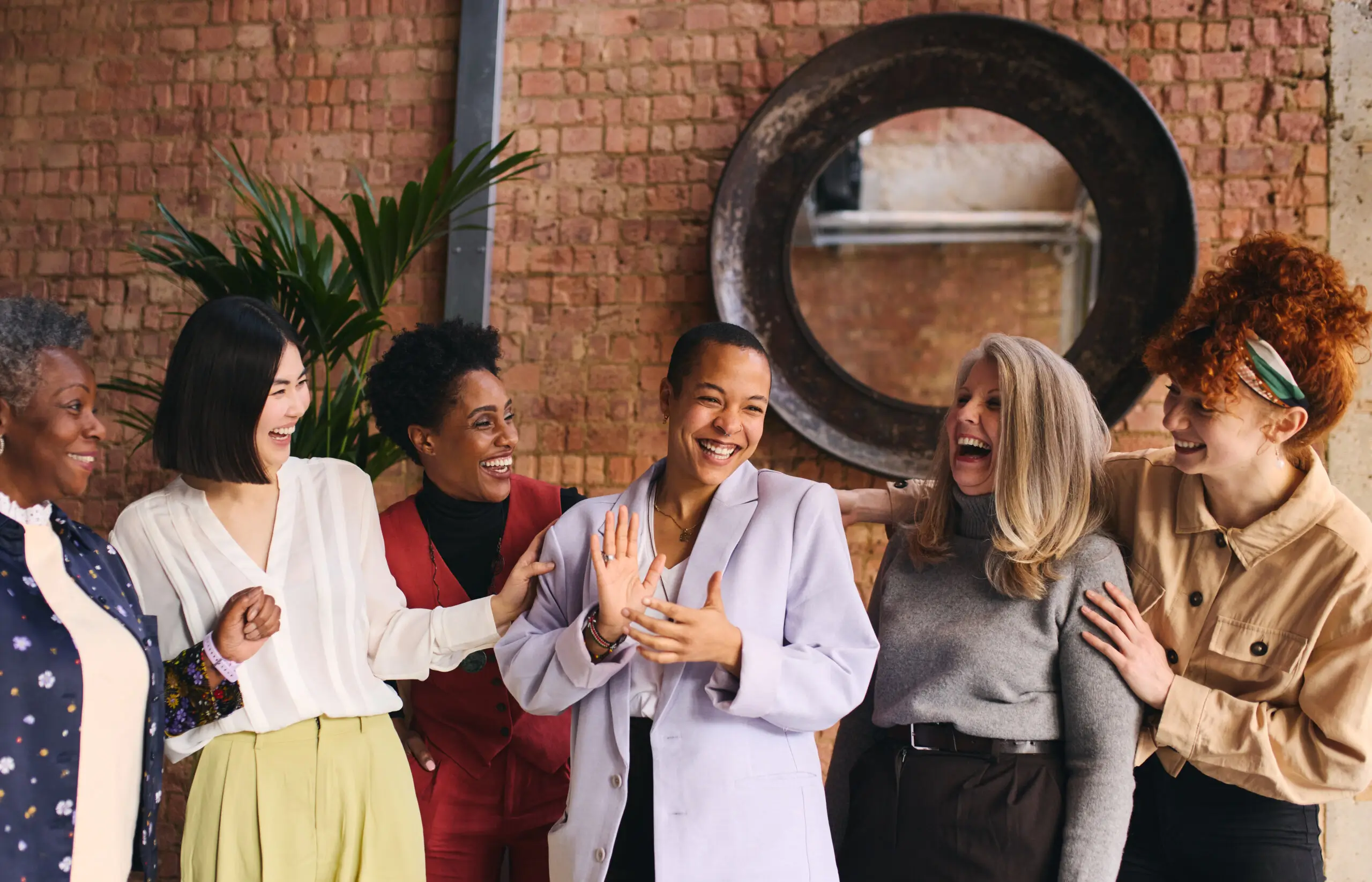 Diverse businesswomen smiling and laughing with each other.