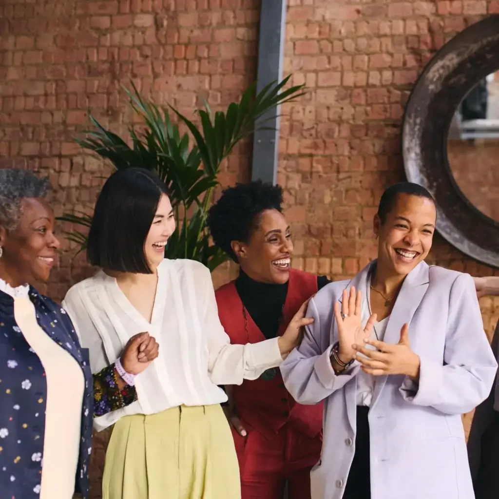 Diverse businesswomen smiling and laughing with each other.